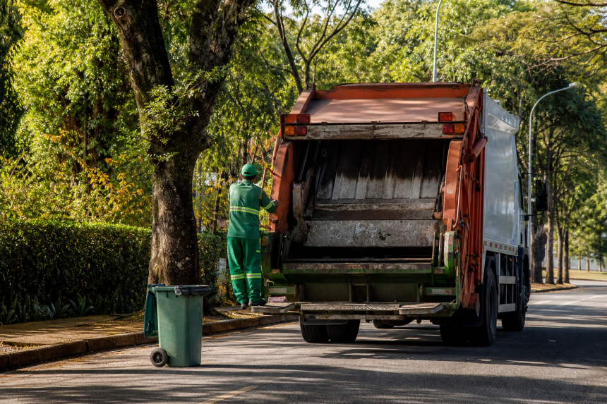 Caminhão de coleta de resíduos circula por rua arborizada de Porangaba, no interior de São Paulo