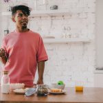 Homem prepara um café da manhã saudável com diversos ingredientes em uma cozinha moderna.