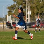 Jogadora de futebol em ação durante uma partida ao ar livre.